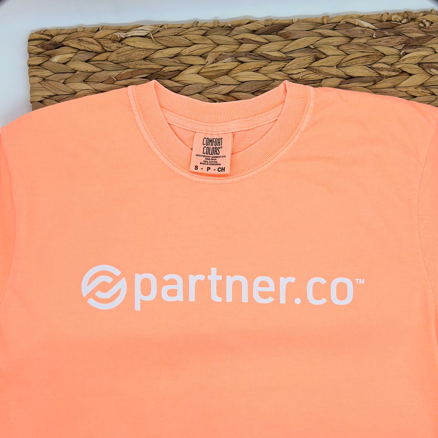 A neon cantaloupe short sleeve t-shirt with the 'partner.co' logo printed in white on the front.