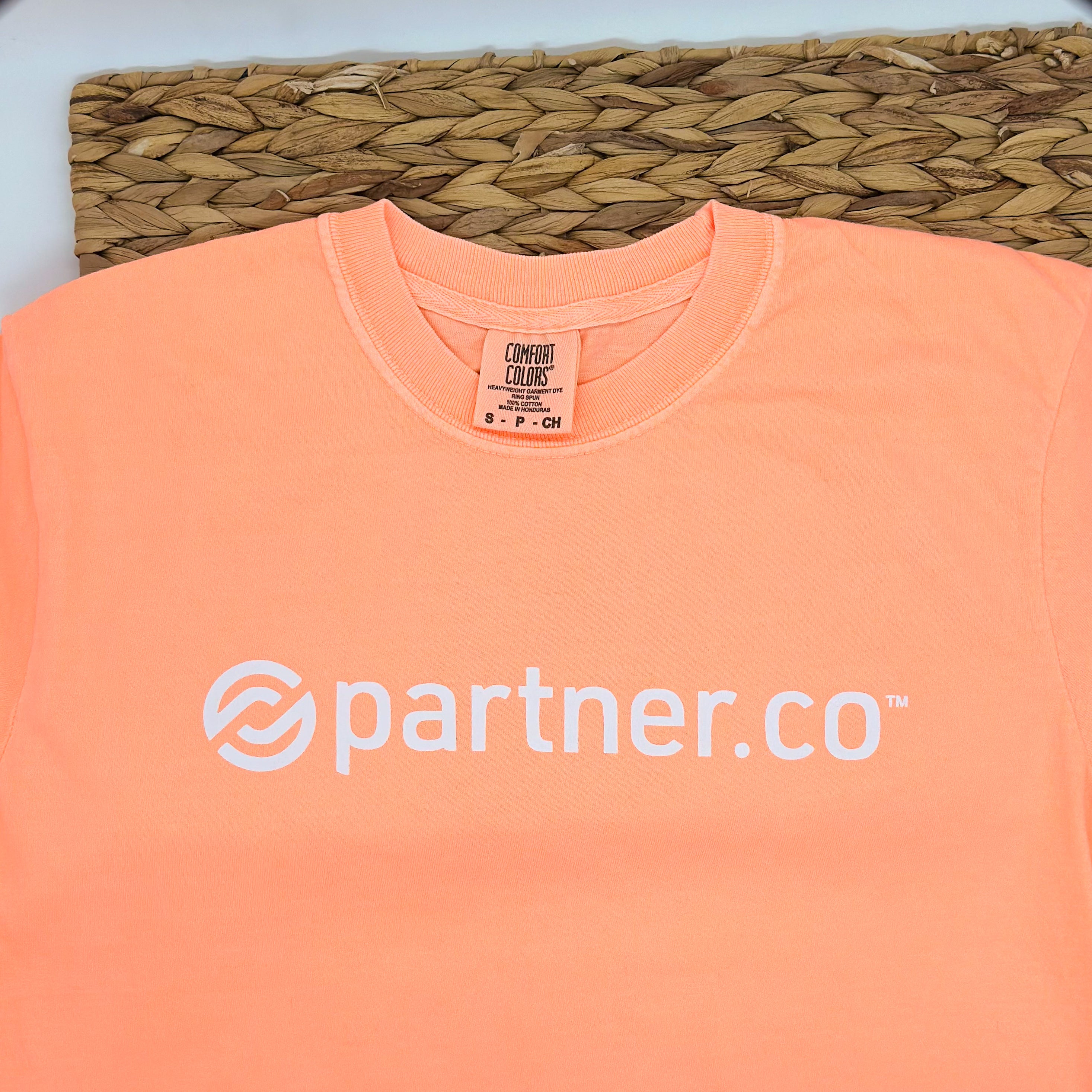 A neon cantaloupe short sleeve t-shirt with the 'partner.co' logo printed in white on the front.