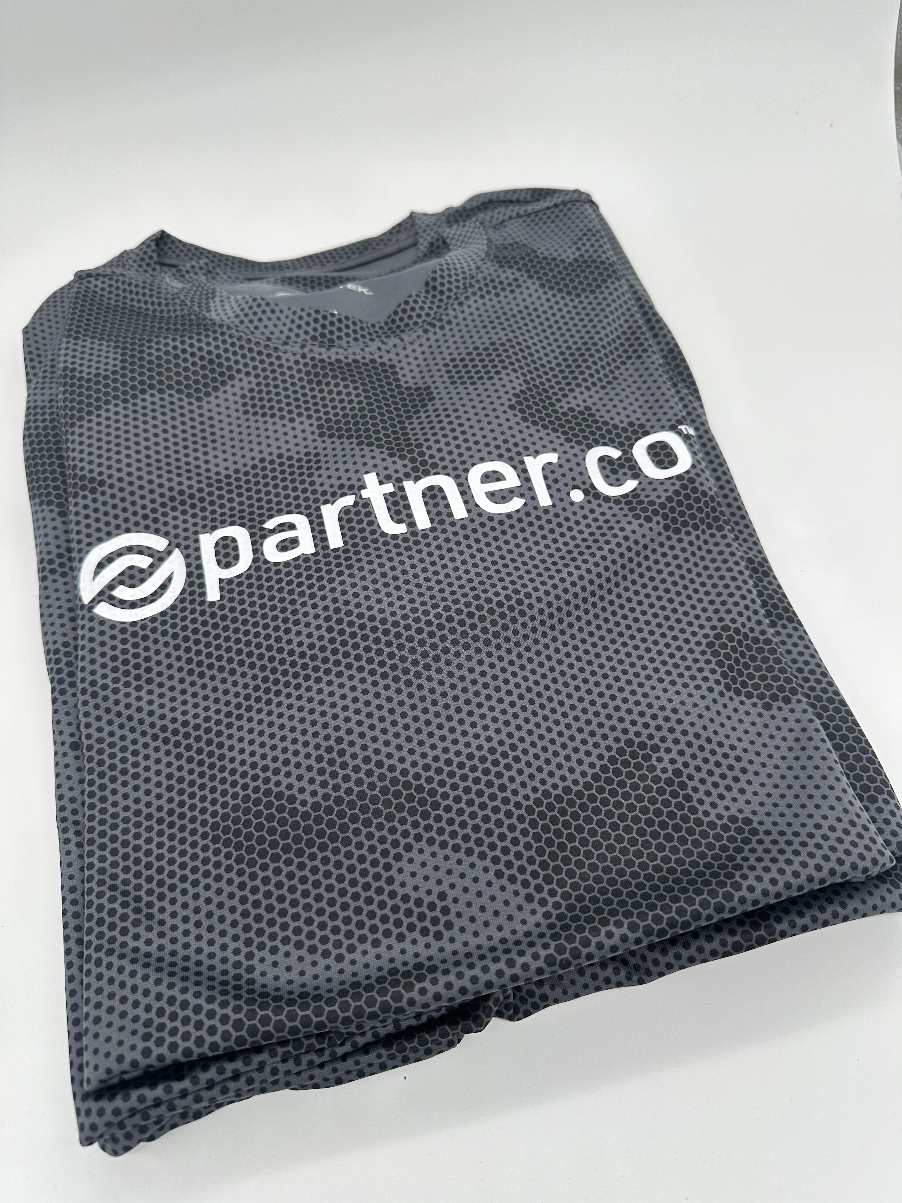 A gray camouflage pattern performance tee with the text 'partner.co' printed on the front.