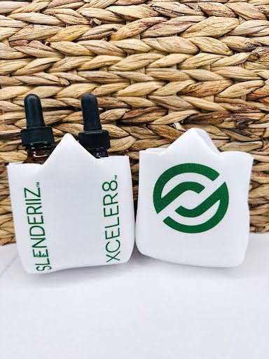Two skinny drops bottle holders with printed designs, one in white with a green design and the other in white with a black design, displayed against a woven background.