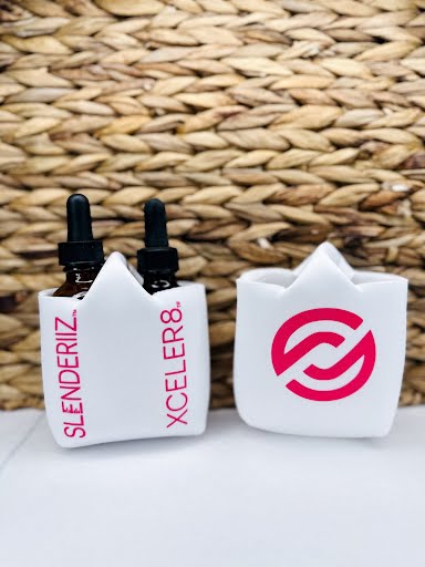 Two skinny drops bottle holders with printed designs, in white with a pink design, displayed against a woven background.