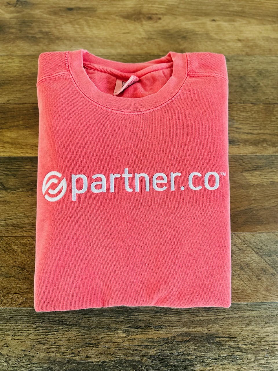 A folded red sweatshirt with the text 'partner.co' embroidered on the front.